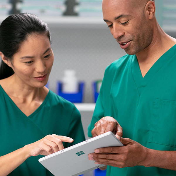Two healthcare professionals interact with a tablet device.